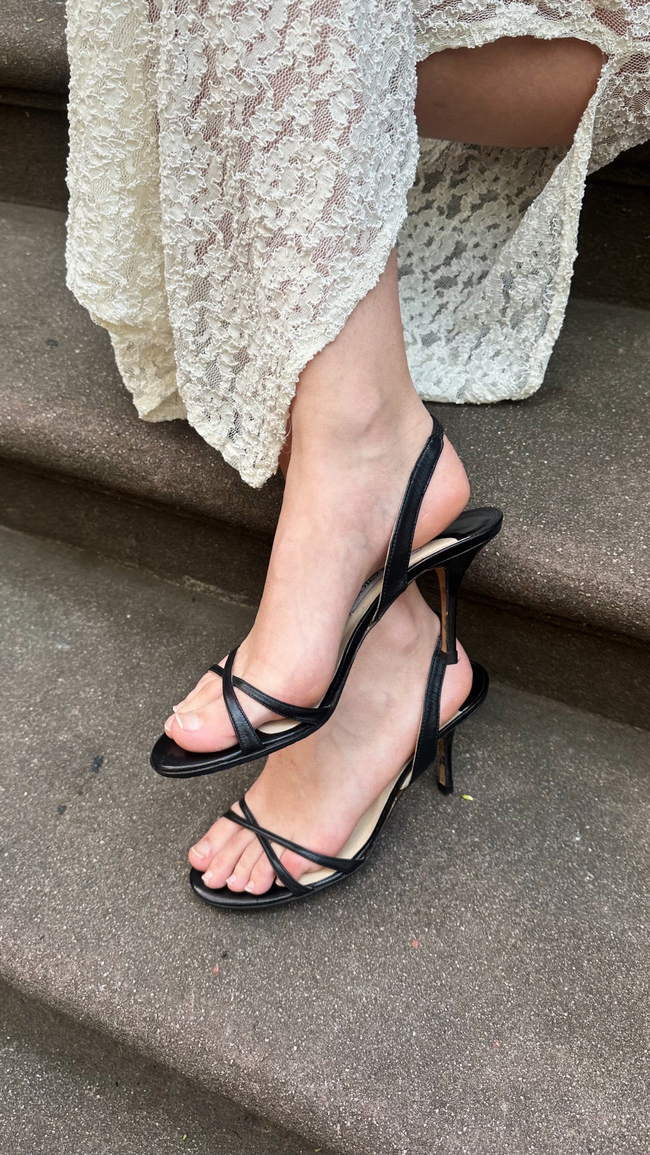 Black strappy high-heeled sandals worn on a staircase